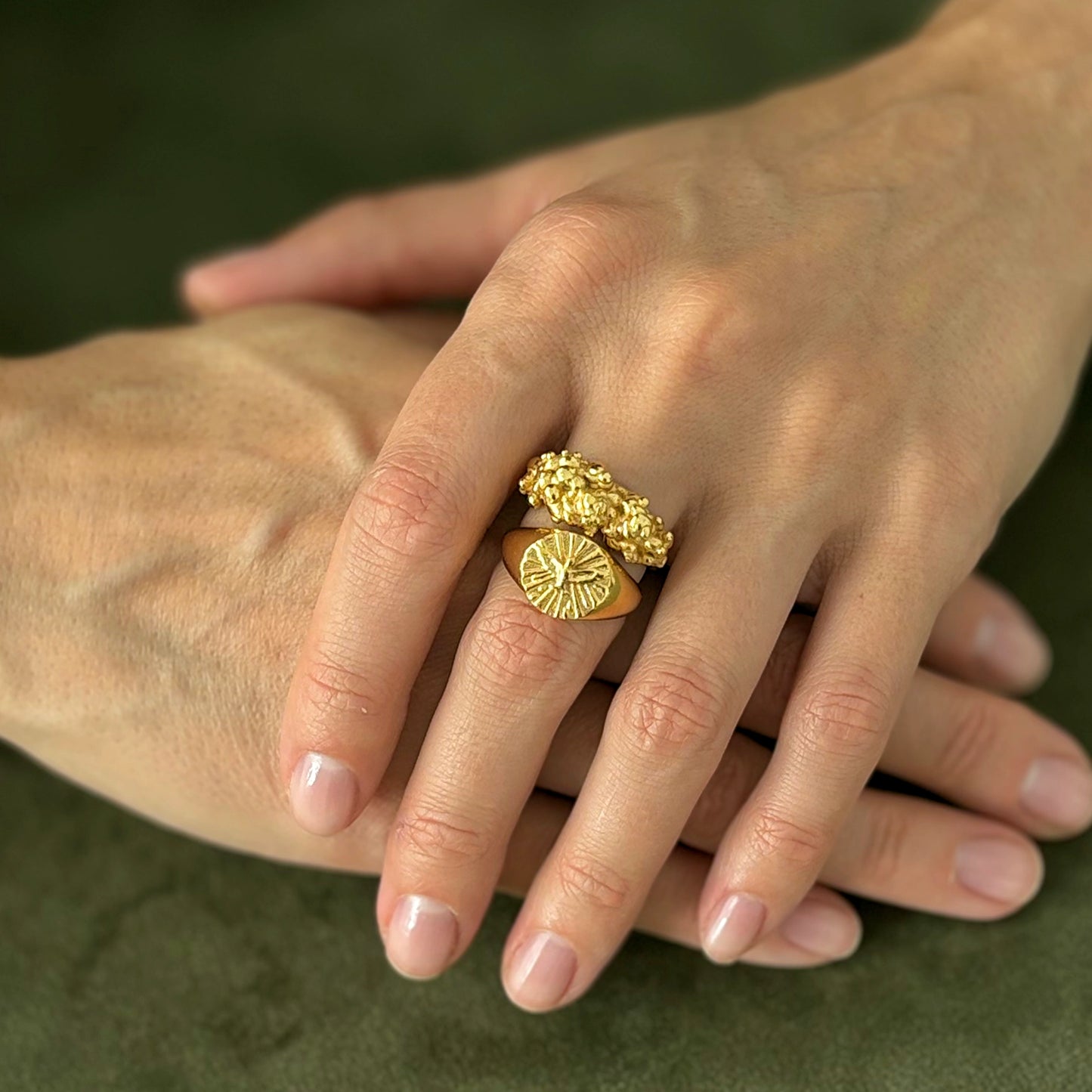 Close-up of a hand wearing a gold ring on a green background
