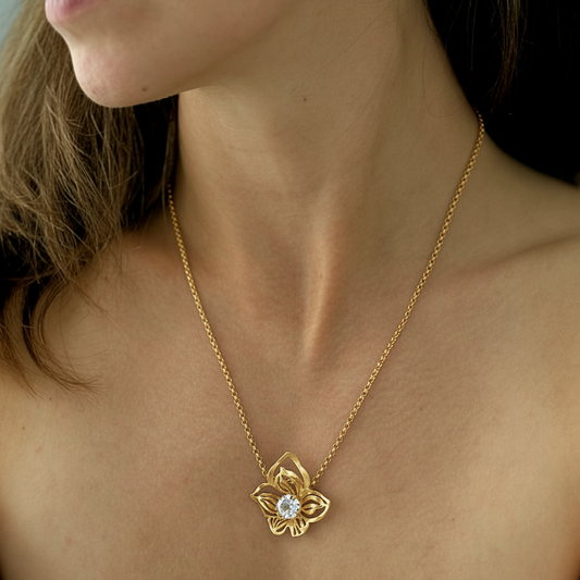 golden chain with orchid pendant with clear crystal worn by brunette female model