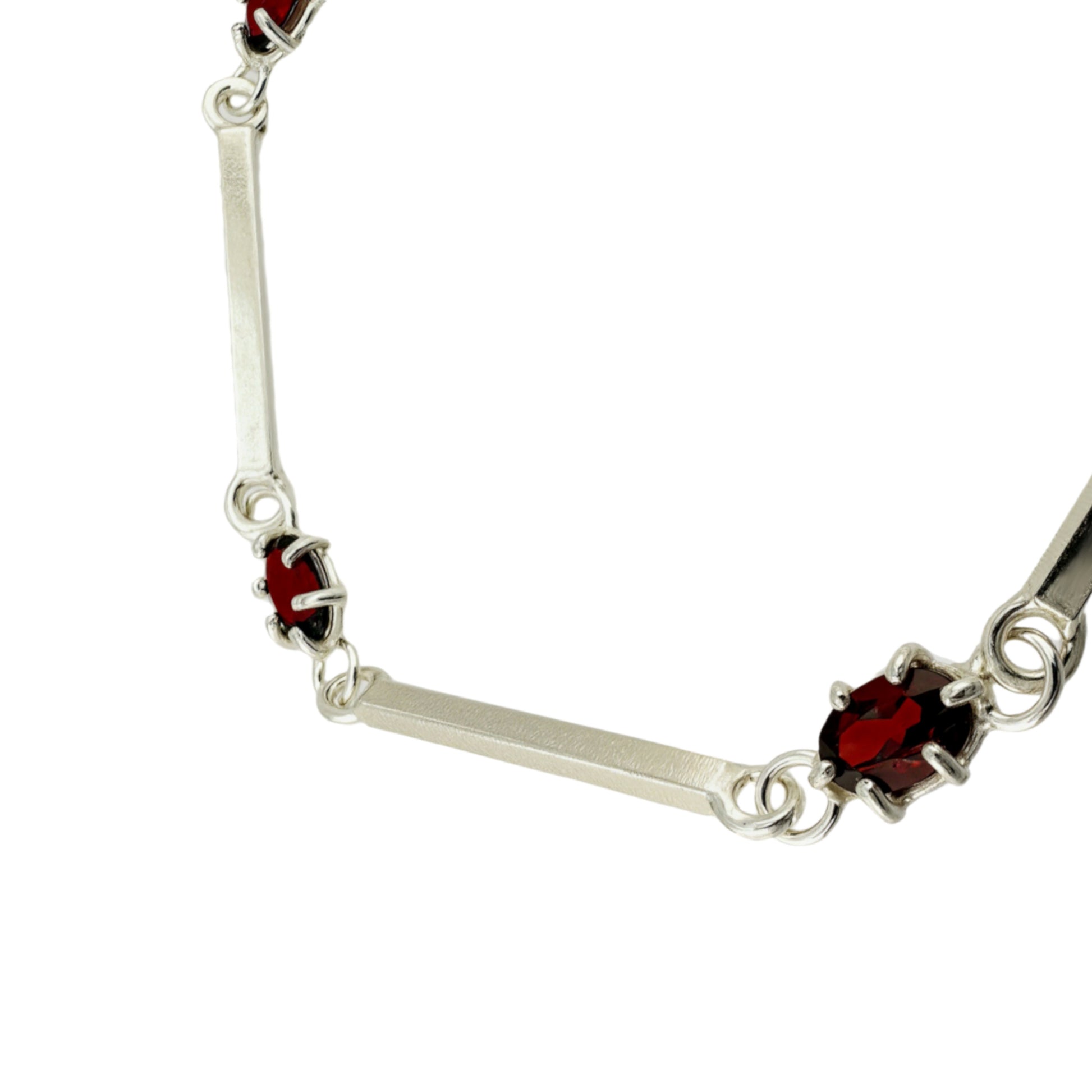 close-up of a silver bracelet with red zirconias on a white background