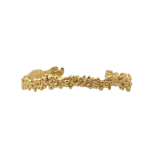 Gold bracelet with organic textured design on a white background