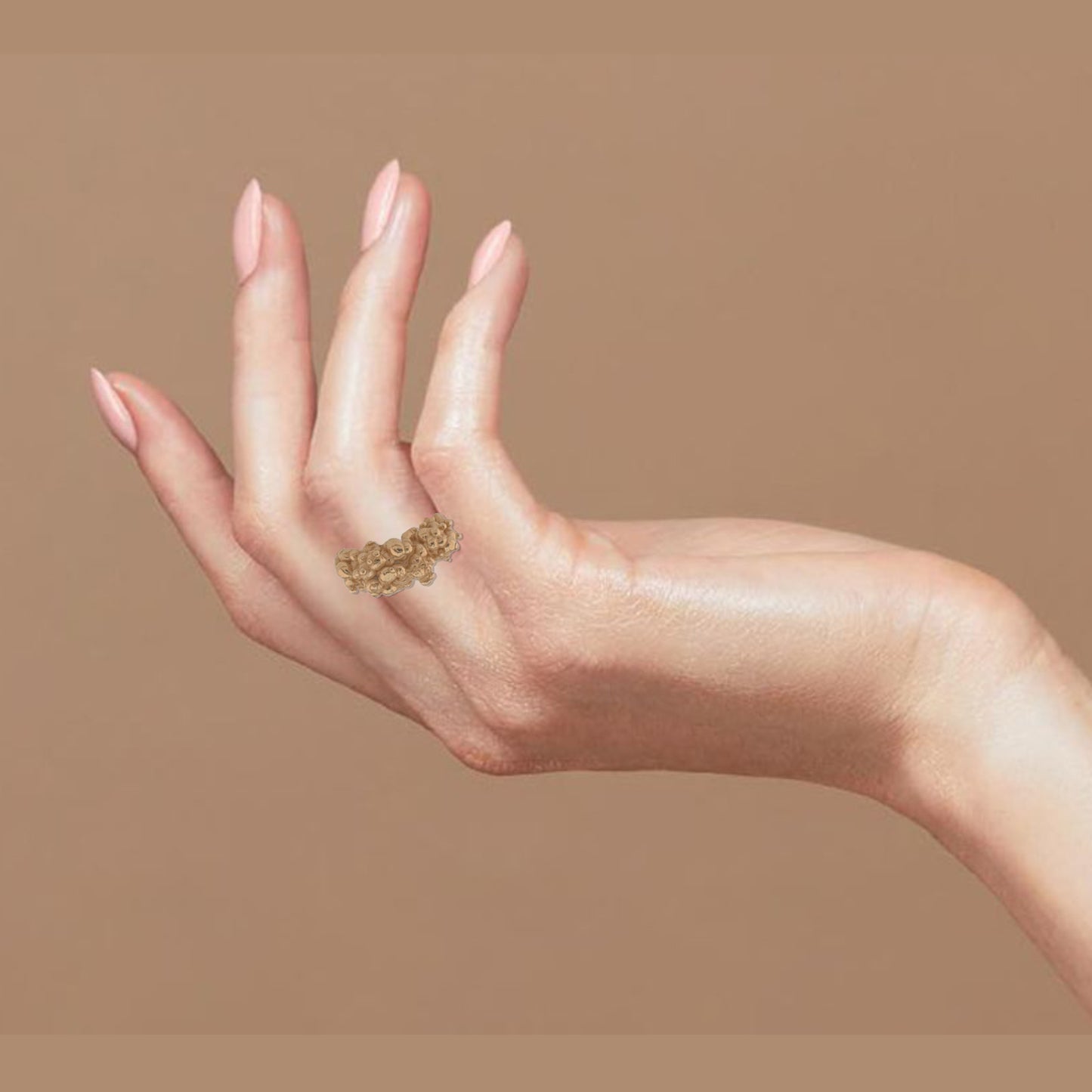 Hand wearing a hand-crafted golden ring with an organic shape