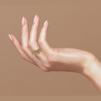 Hand wearing a hand-crafted golden ring with an organic shape