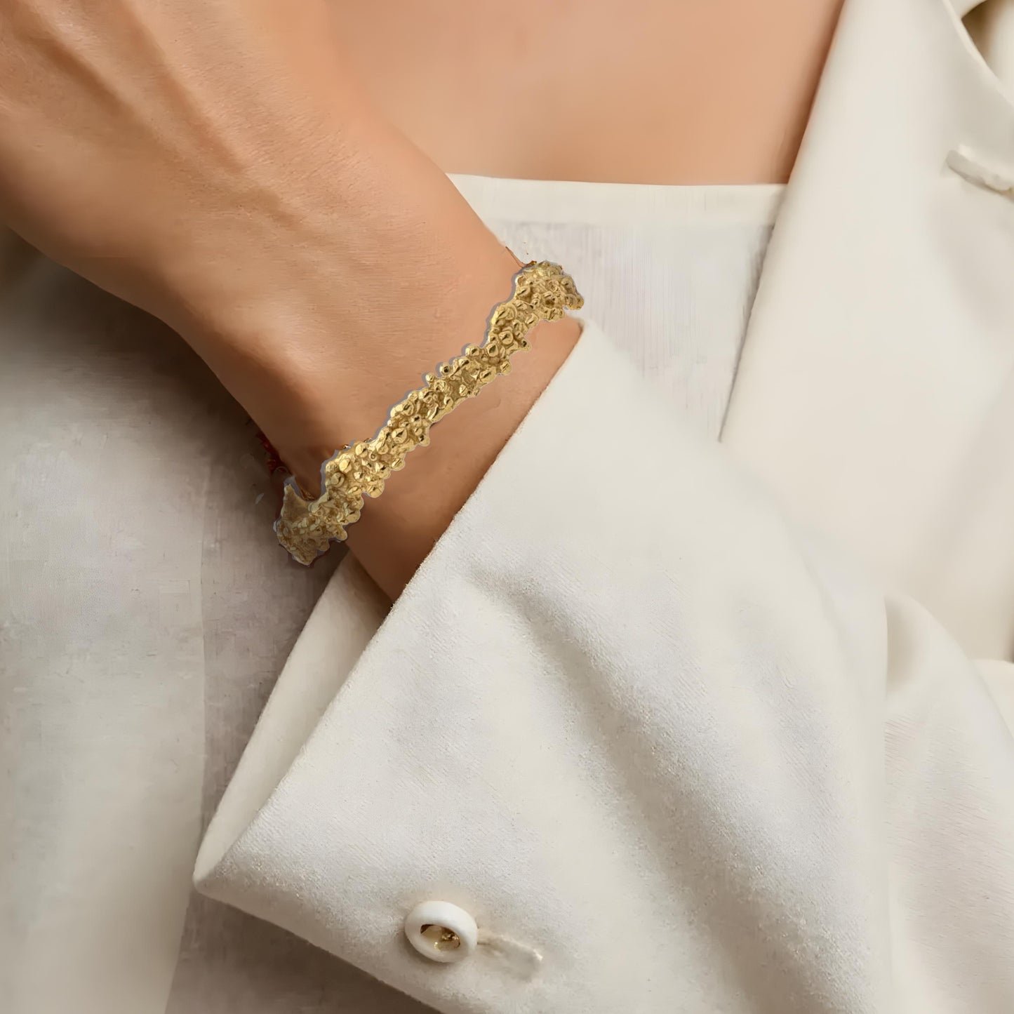 Handcrafted golden bracelet with organic shape on wrist. 