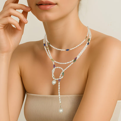 Pearl necklace with colorful beads worn by a woman on a neutral background