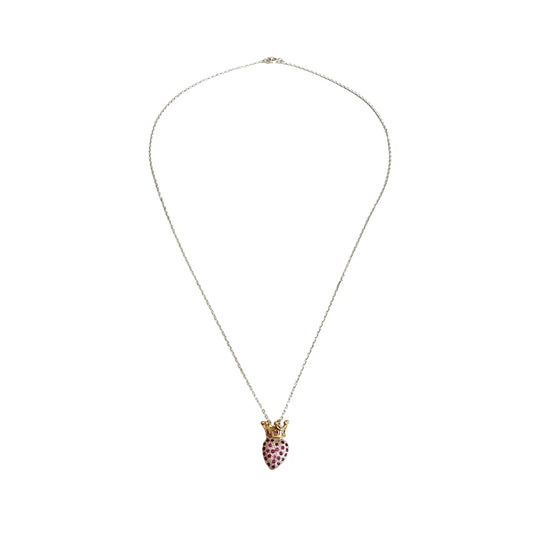 A long silver chain with a heart shaped pendant encrusted with red zirconias and topped with a gold crown.