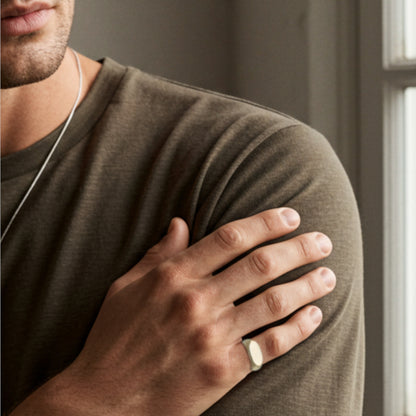 Minimalist silver signet ring worn on finger, bold everyday style