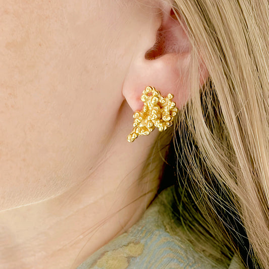 Gold earring worn by a person with blonde hair