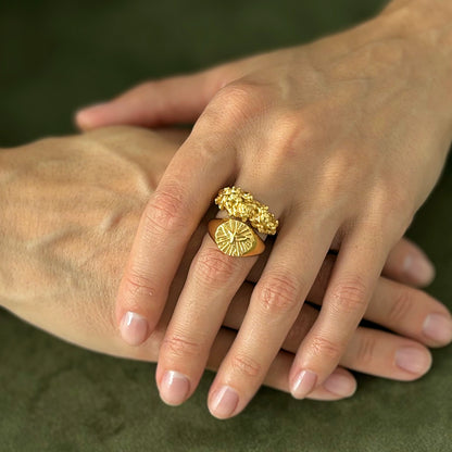 Close-up of a hand wearing a gold ring on a green background