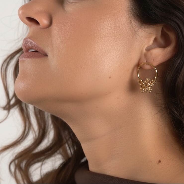 brunete model with long curly hair wearing golden hoop earrings with organic detail
