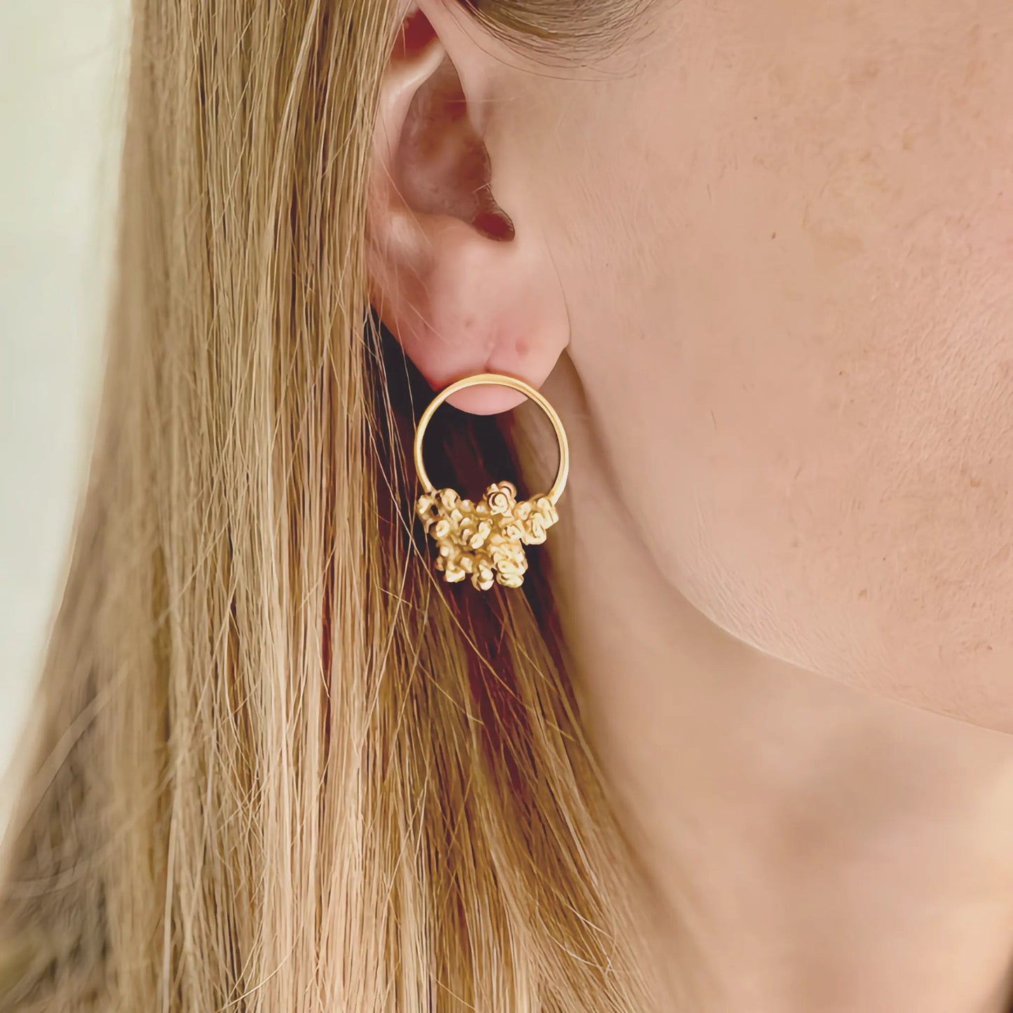 blond women wearing golden hoop earrings with organic details