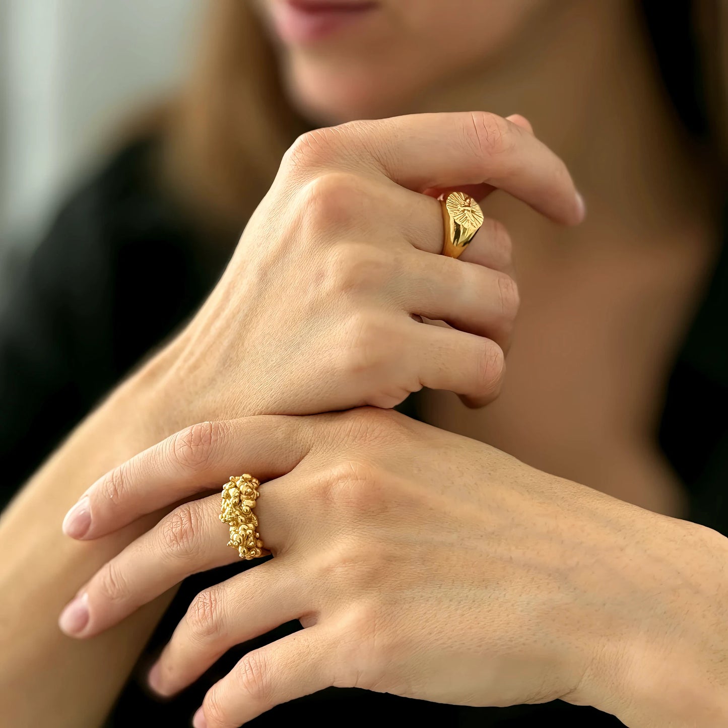 Close-up of hands wearing gold rings with a blurred background
