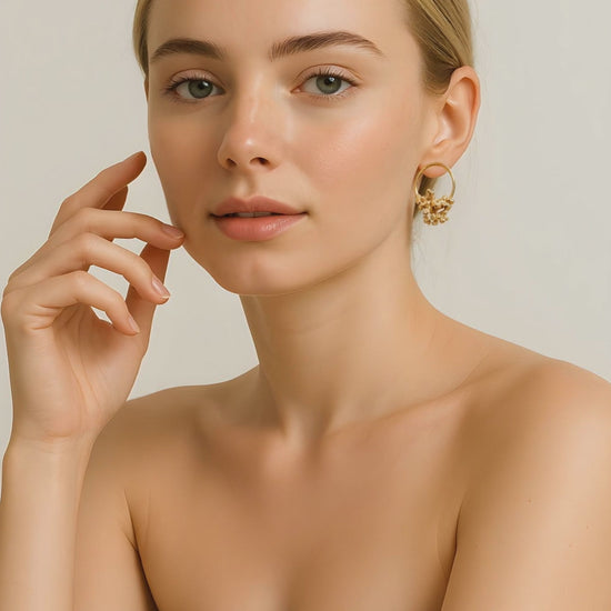 A woman wearing a hoop stud golden earrings with coral-like details and smiling to the camera