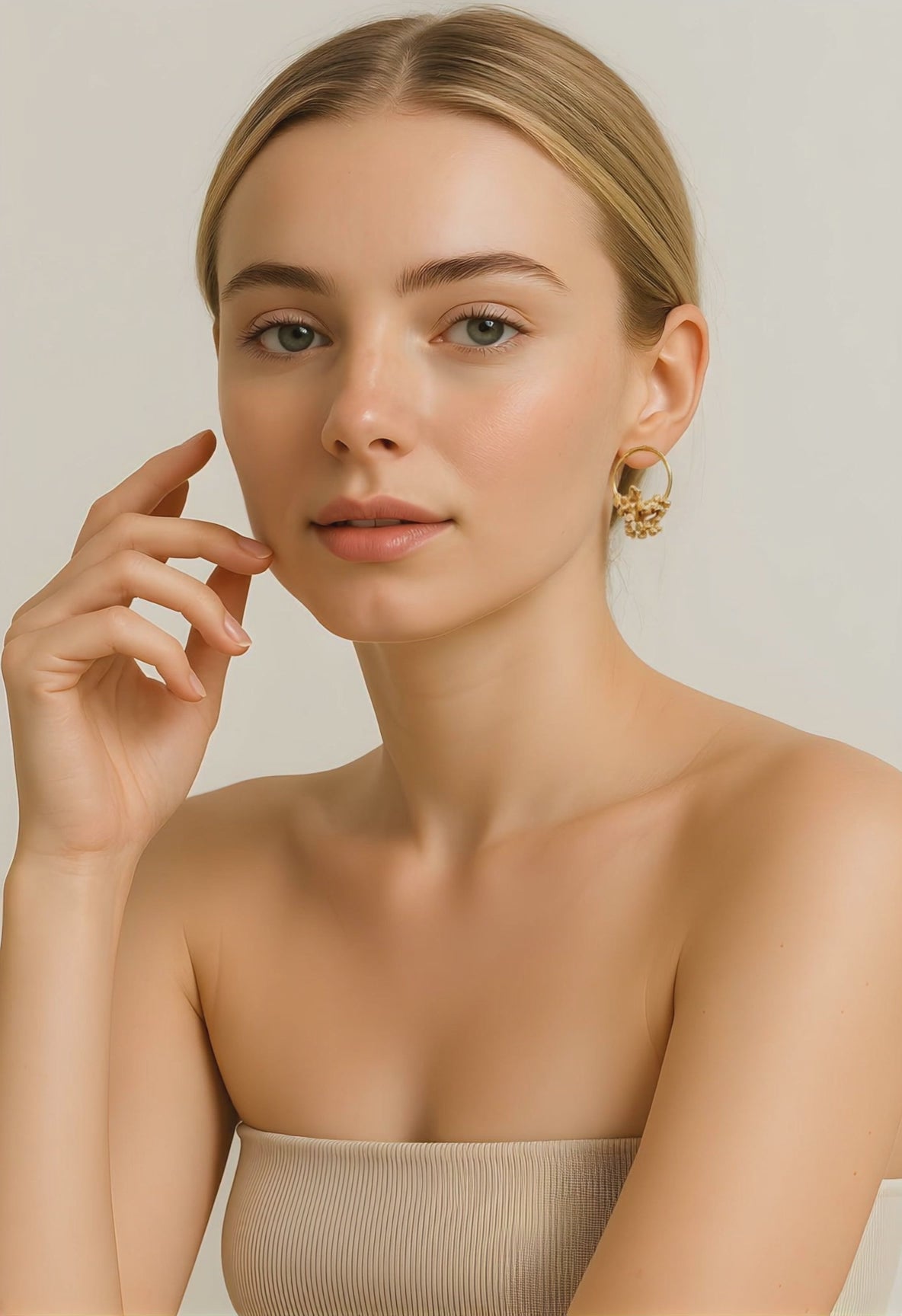 A woman wearing a hoop stud golden earrings with coral-like details and smiling to the camera